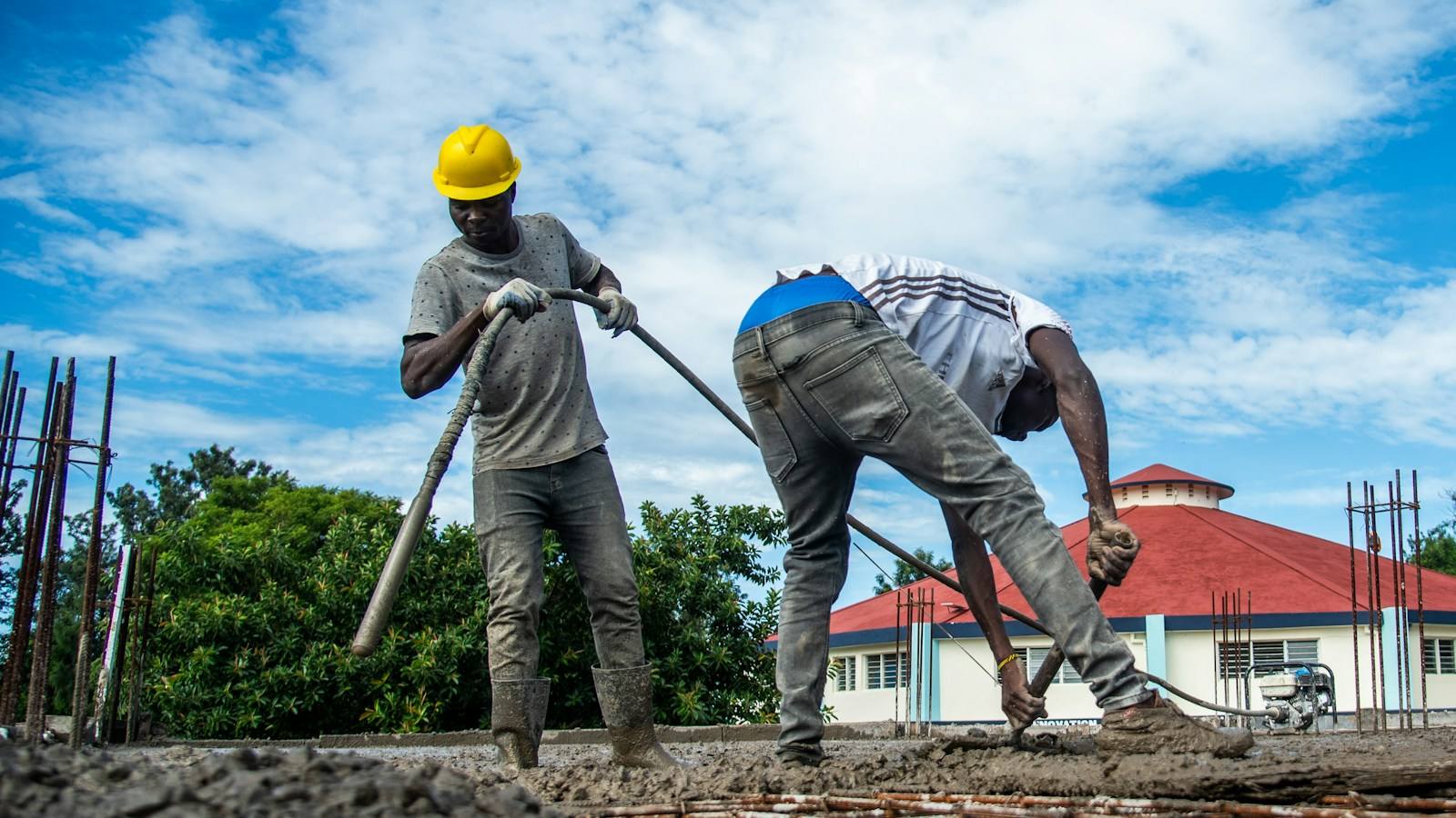 Concrete crew screeding and finishing a freshly poured slab in full sun