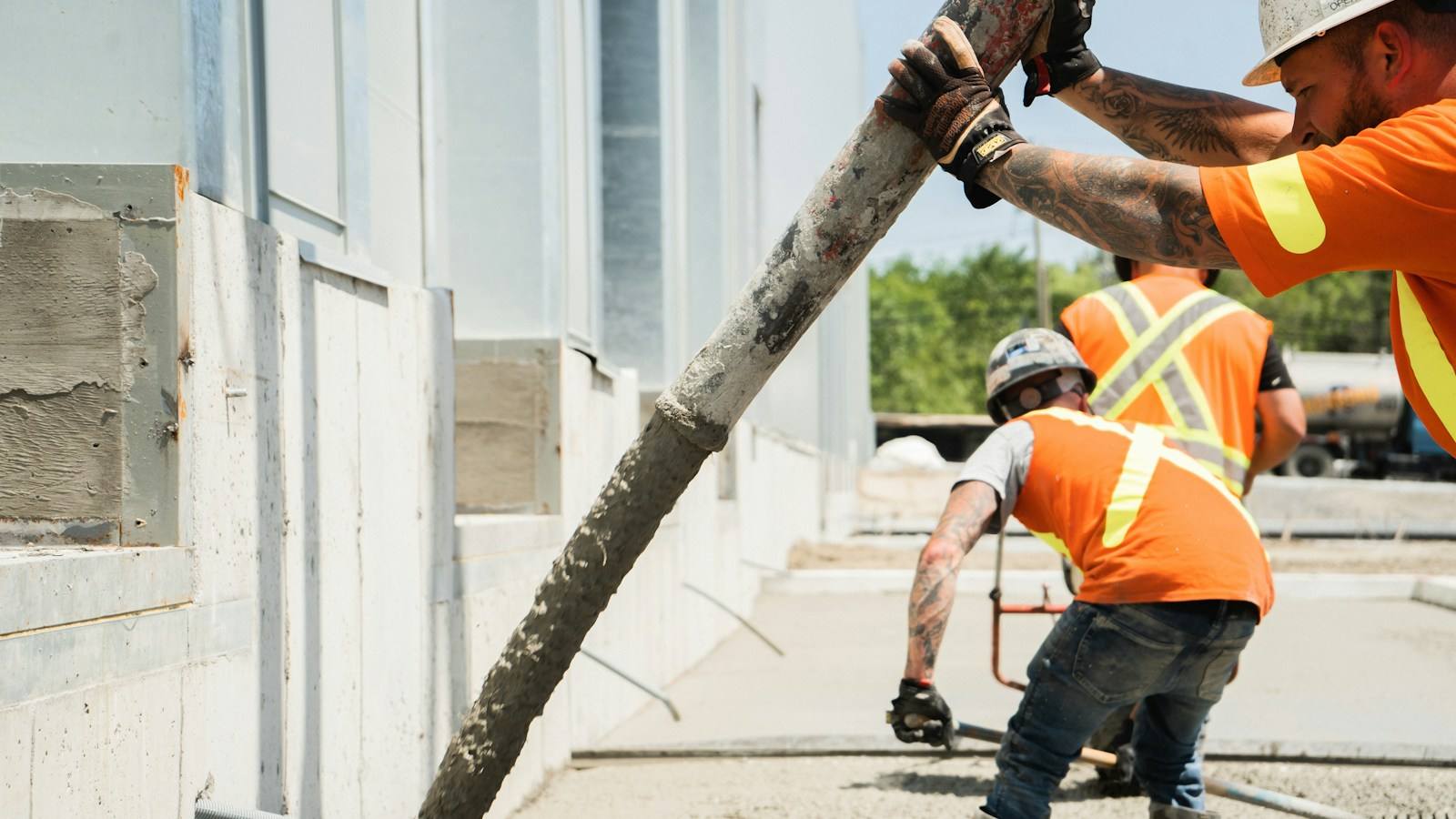Concrete placed from a pump hose across a prepared slab area while a worker guides the flow