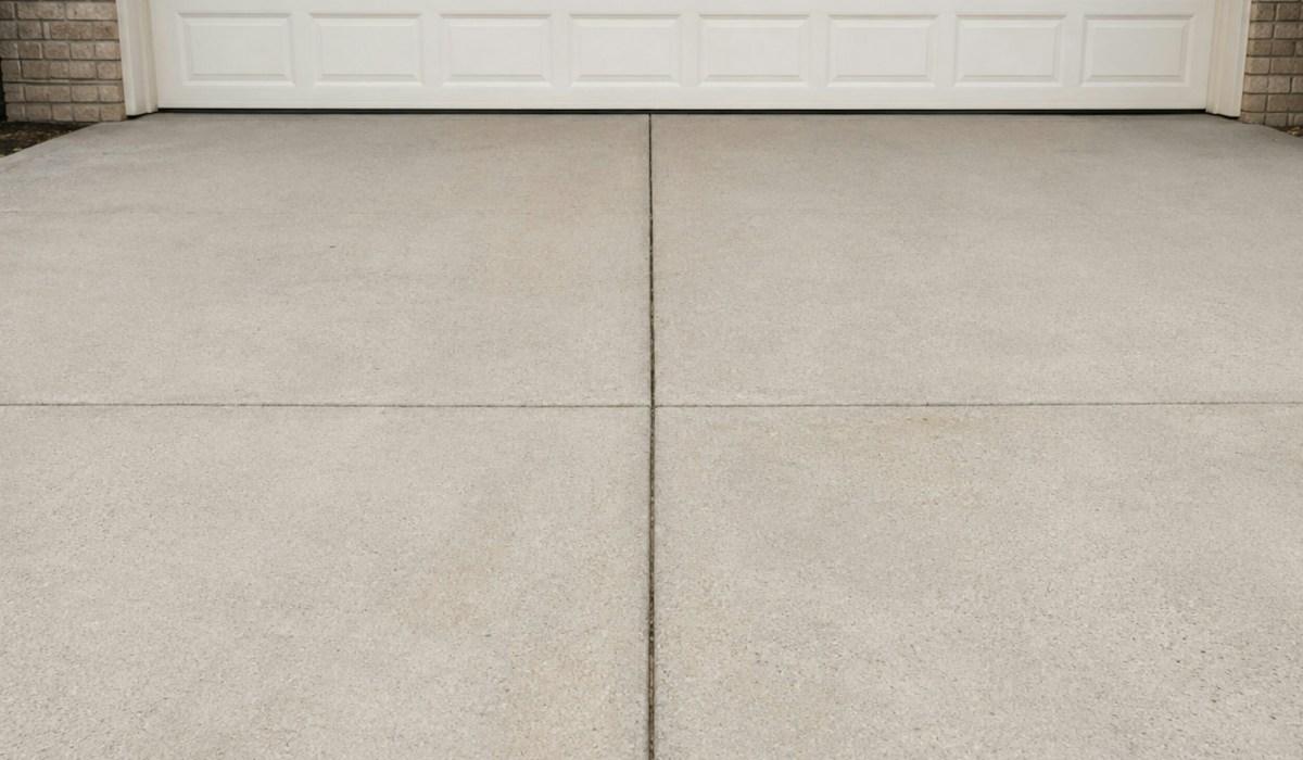A clean concrete driveway leading up to a white garage door