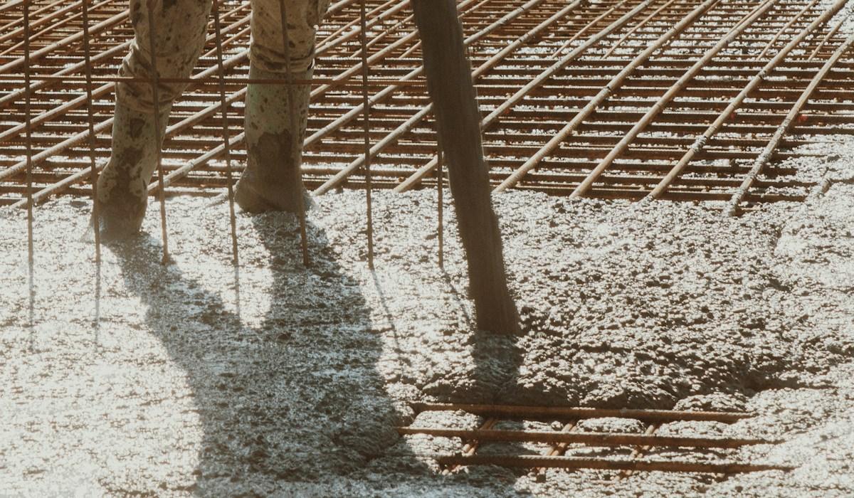 A worker standing on a large finished concrete slab at a building site